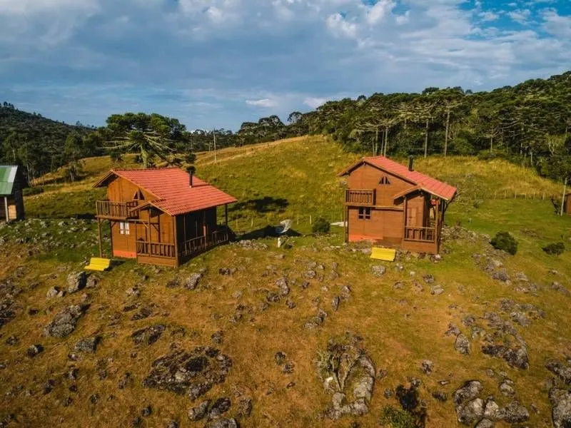Vista aérea de dois chalés de madeira em meio aos campos do Costão do Cambará Hotel Fazenda