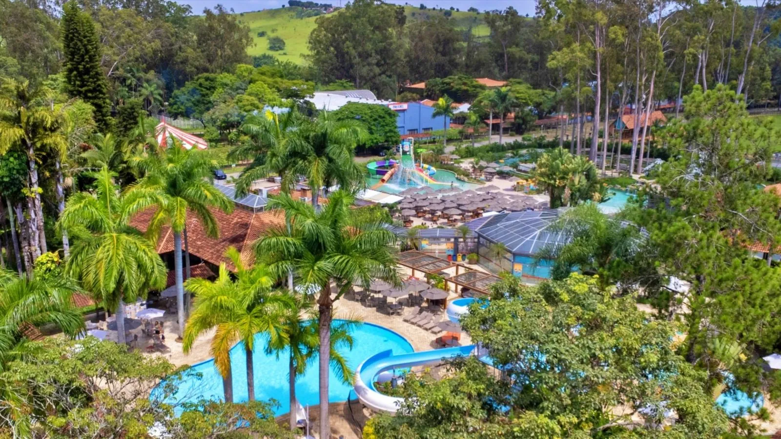 Vista aérea das piscinas, toboágua e parque aquático do Hotel Fazenda Mazzaropi, com o circo ao fundo
