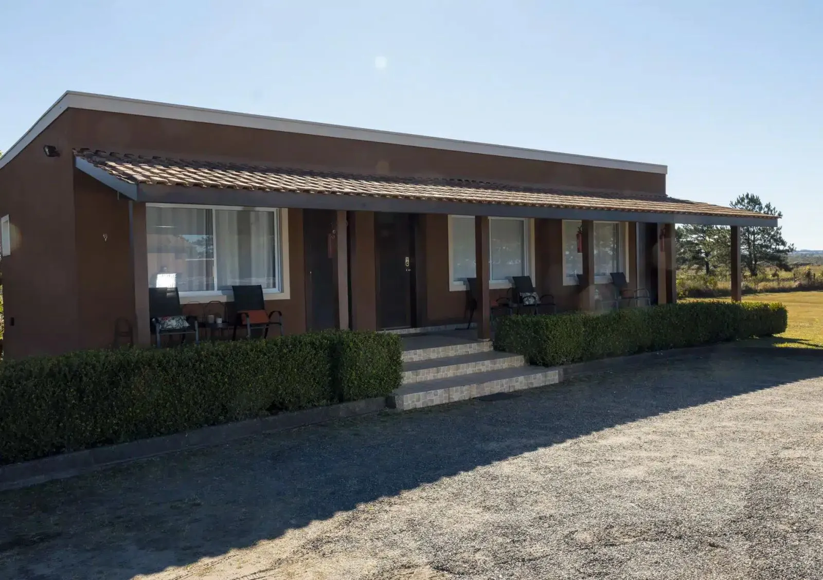 Fachada de um dos chalés do Hotel Fazenda Cainã, com varanda coberta e escada de acesso