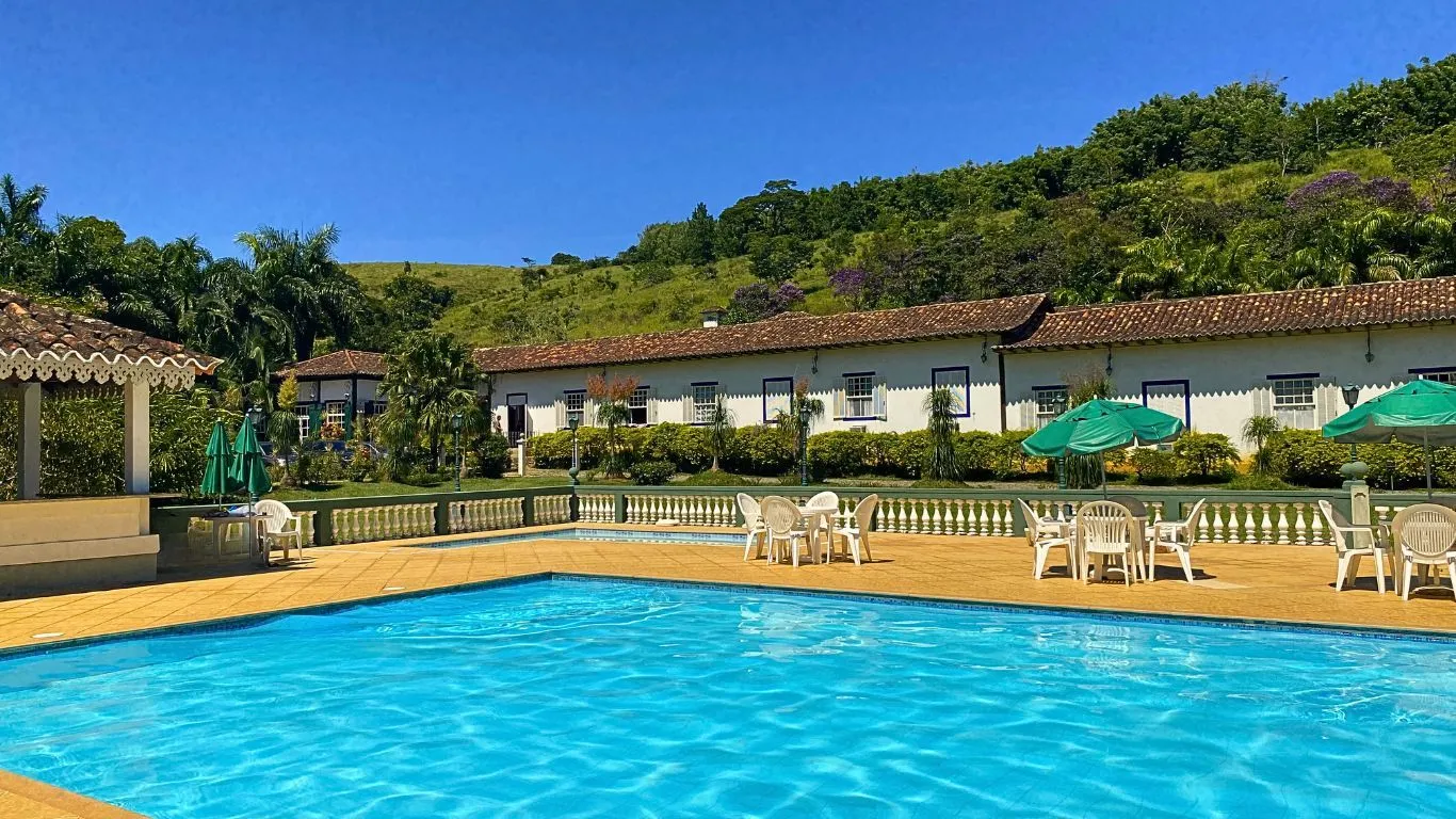 Piscina e casarão colonial do Hotel Fazenda Florença com serra ao fundo