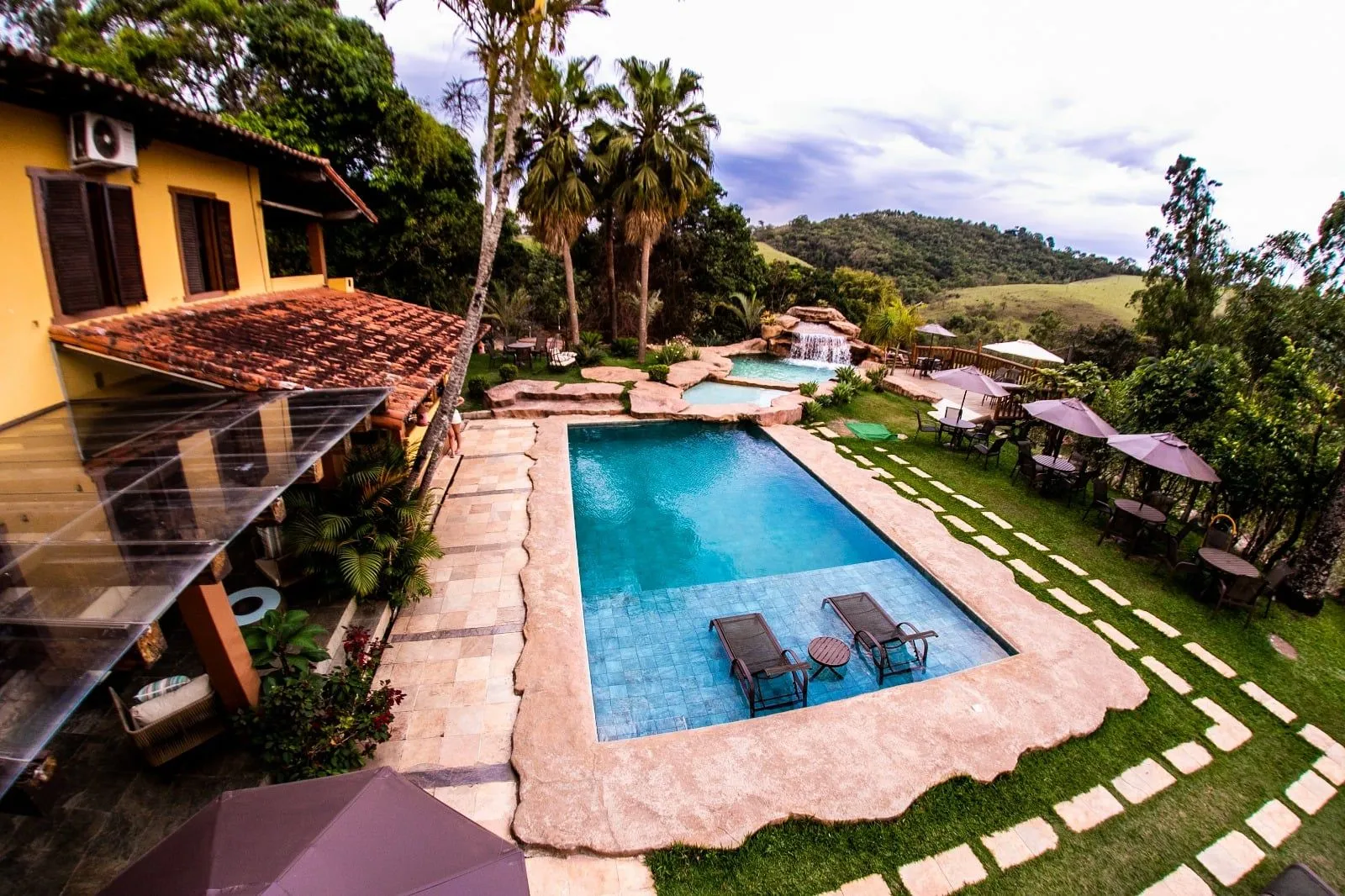 Vista aérea da piscina com cascata e do casarão do Hotel Fazenda Horizonte Belo, em Brumadinho