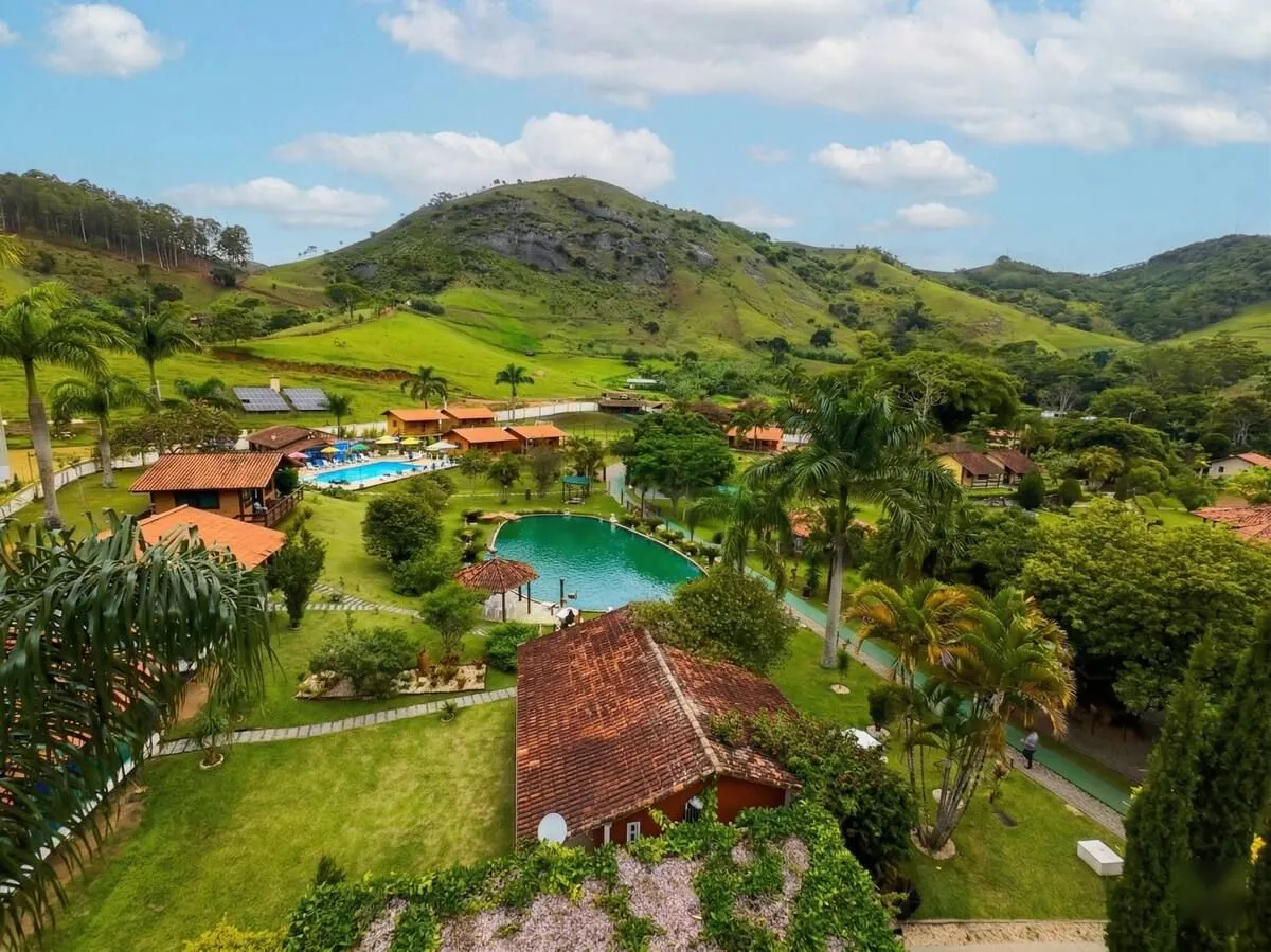 Vista aérea do Minha Glória Hotel Boutique com piscinas, chalés e serra ao fundo