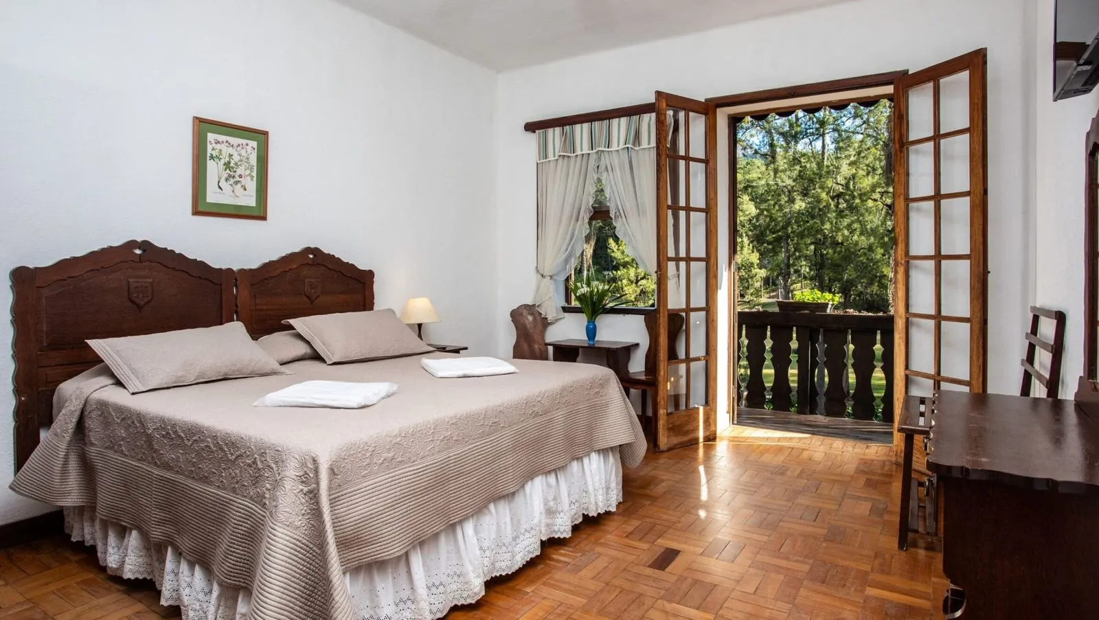 Suíte standard do Hotel Fazenda São Moritz com cama de casal e varanda para o bosque