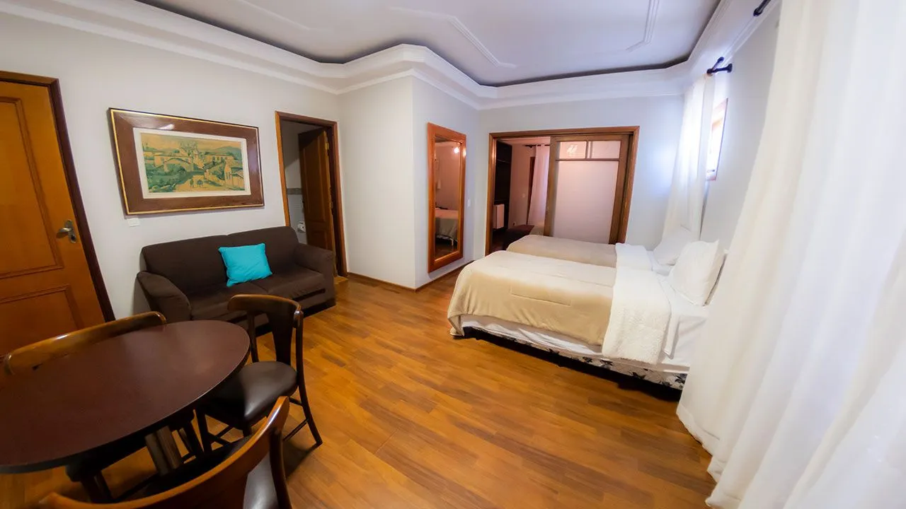 Suíte master do Hotel Fazenda Poços de Caldas com duas camas e sala de estar integrada