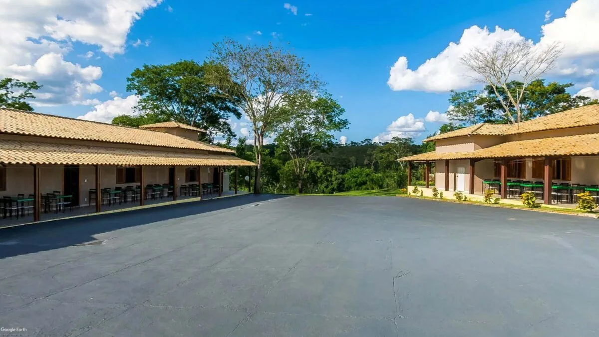 Pavilhões de refeitório com mesas e cadeiras do Sítio Green Valley, cercados por mata