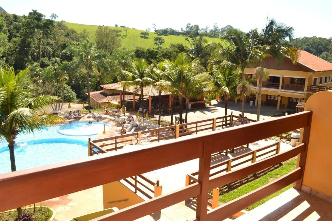 Vista da varanda de um apartamento para a piscina e a área de lazer do Hotel Fazenda Saint Nicolas