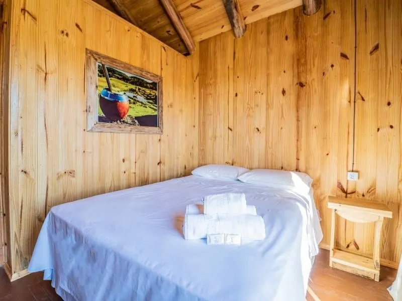 Quarto revestido em madeira com cama de casal no Costão do Cambará Hotel Fazenda