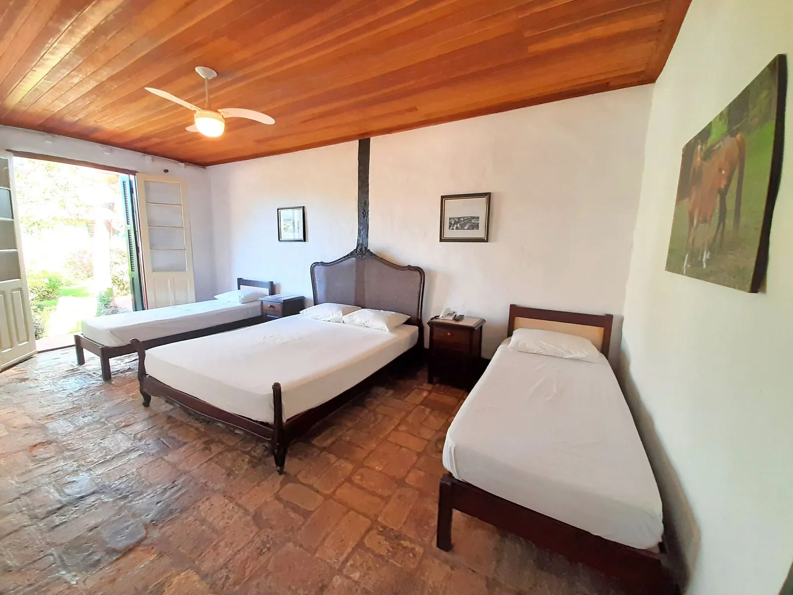 Apartamento com cama de casal e duas camas de solteiro, piso de tijolo antigo e teto de madeira