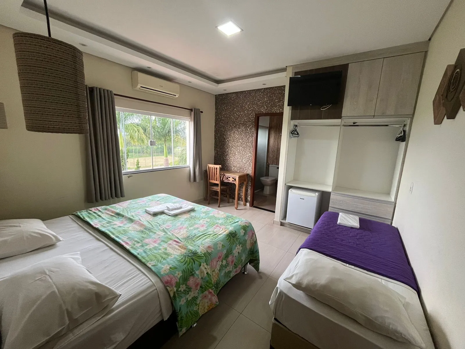 Suíte de casal com cama de solteiro extra, ar-condicionado e vista para o jardim