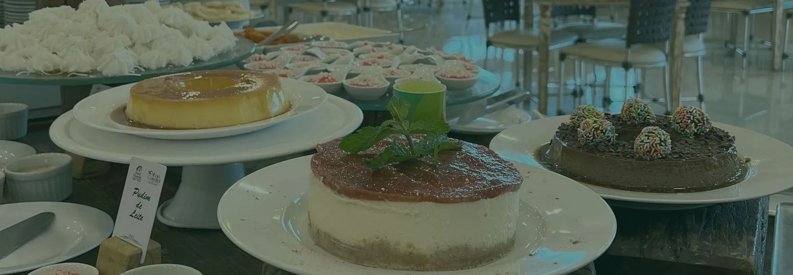 Mesa de sobremesas do buffet com pudim de leite, cheesecake e brigadeirão