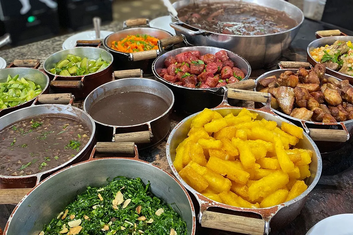 Buffet de comida mineira em panelas com feijão tropeiro, angu, frango e legumes