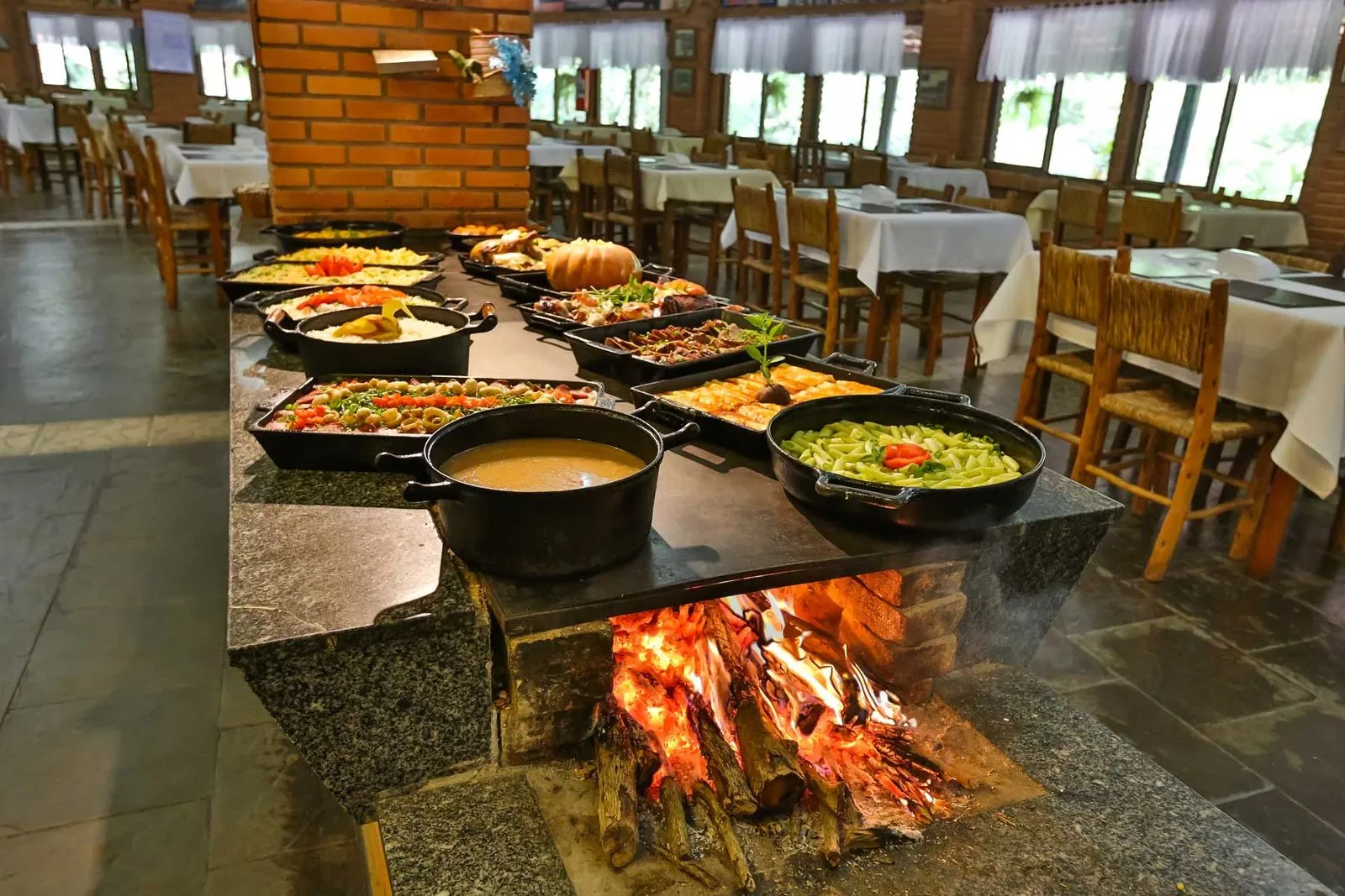 Buffet em panelas de ferro sobre fogão a lenha no restaurante do hotel