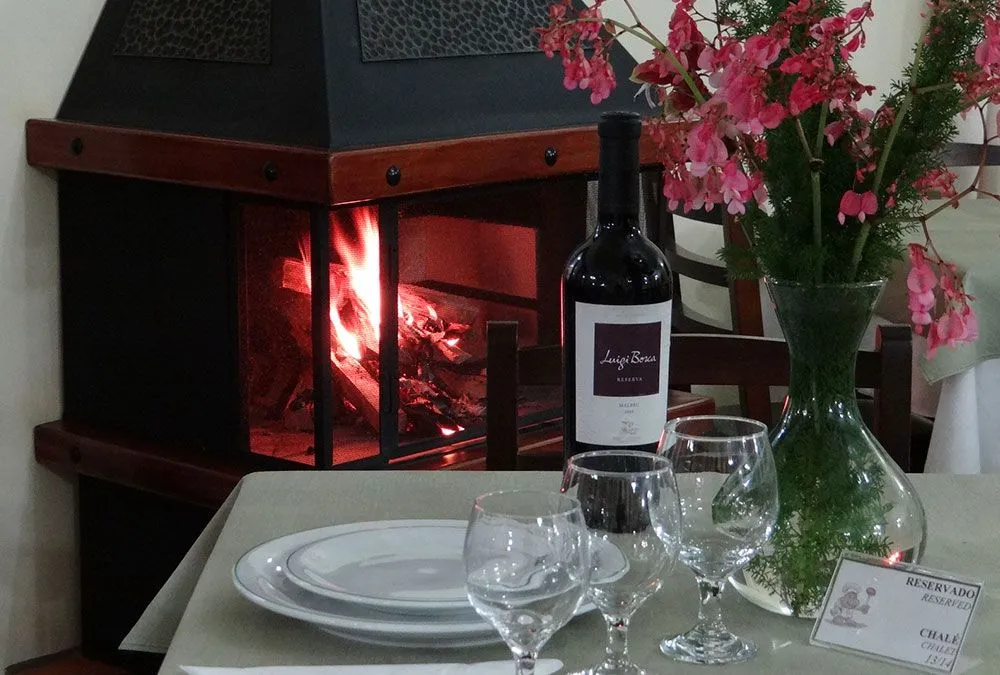Mesa posta com vinho e lareira acesa no restaurante do Hotel Fazenda Itáytyba