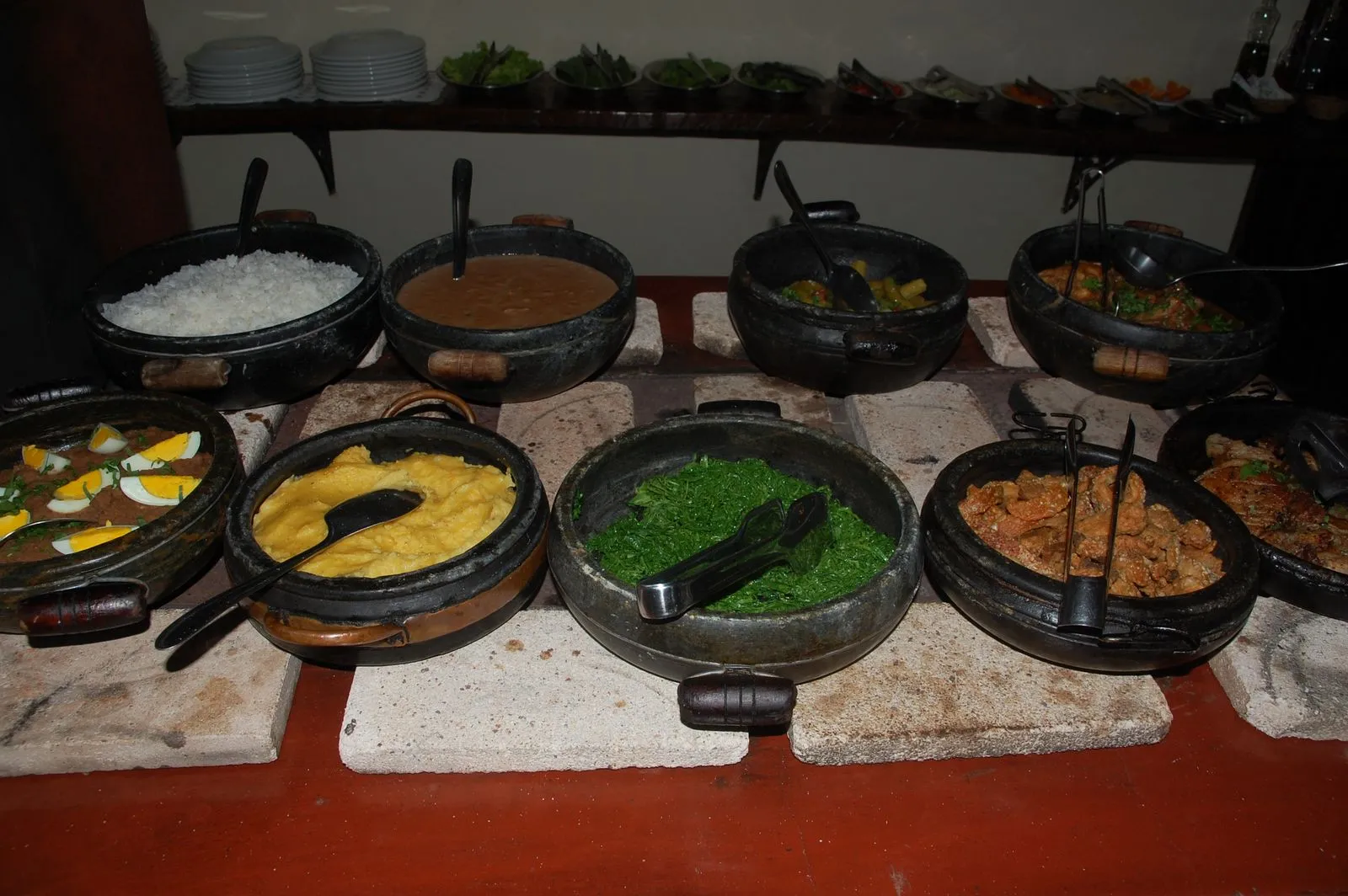 Buffet de comida mineira em panelas de barro, com arroz, feijão, angu e couve