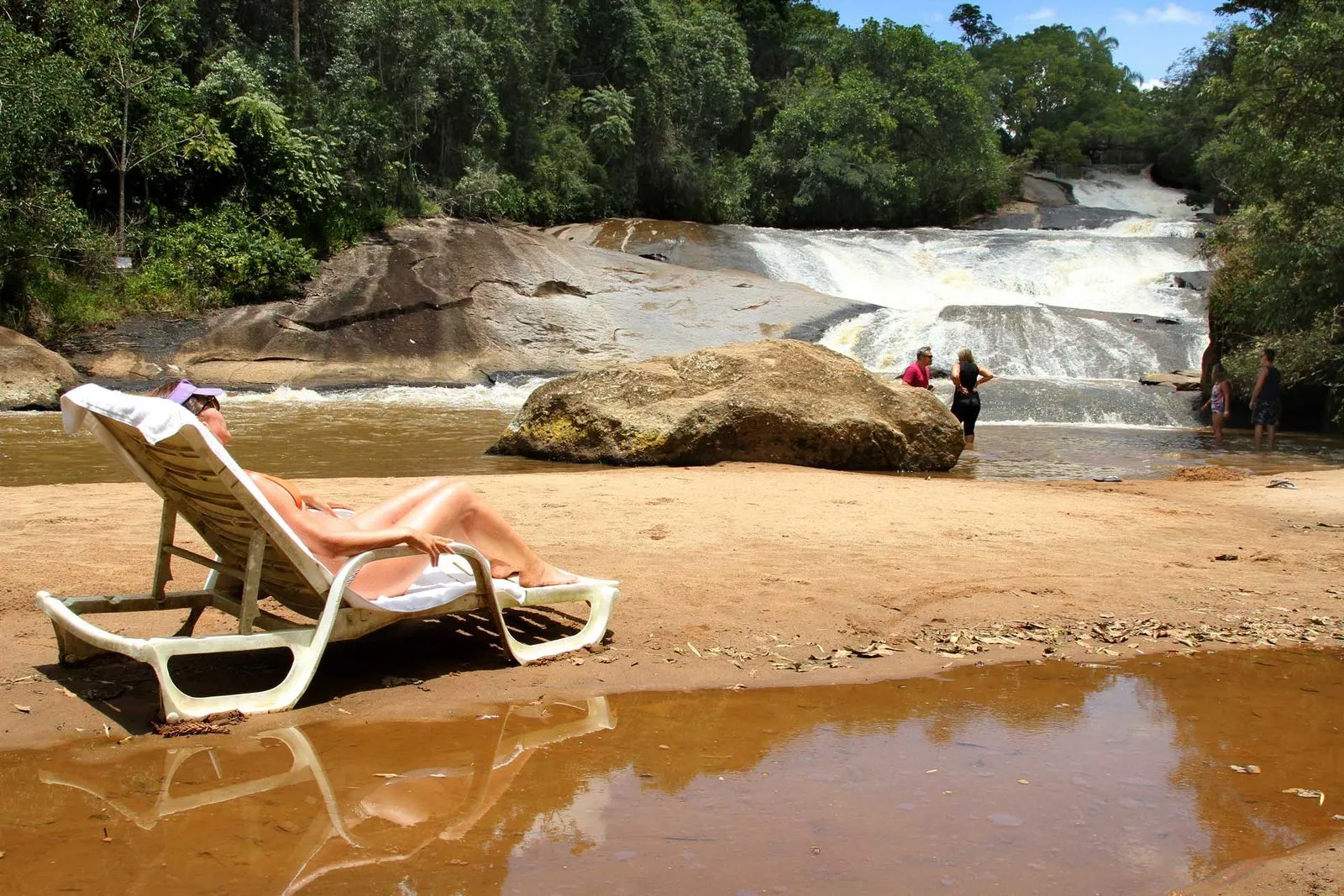 Hóspedes na prainha de areia diante da cachoeira em frente à sede