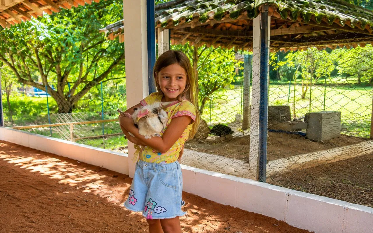 Criança segurando um coelho na fazendinha do Hotel Fazenda Florença