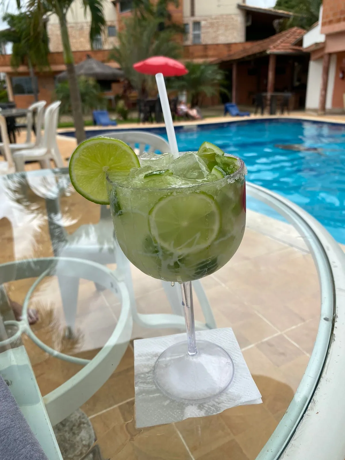 Caipirinha servida à beira da piscina, em mesa com vista para os chalés