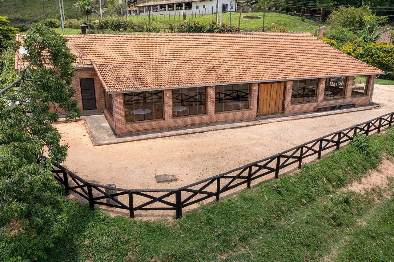Fachada externa do restaurante de tijolo aparente e telhado colonial, vista aérea