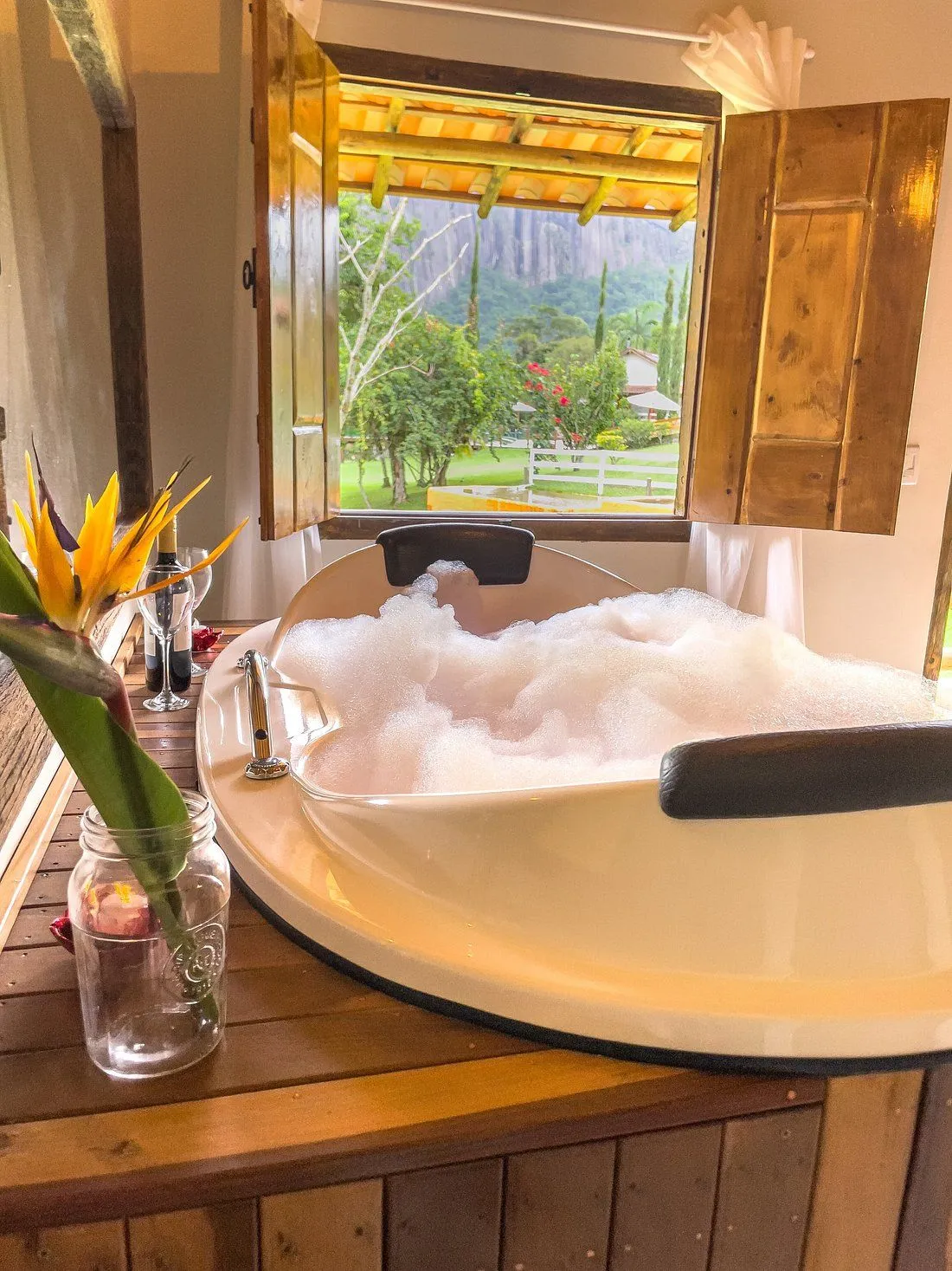 Banheira de hidromassagem com espuma junto à janela com vista para a serra, em chalé do Minha Glória
