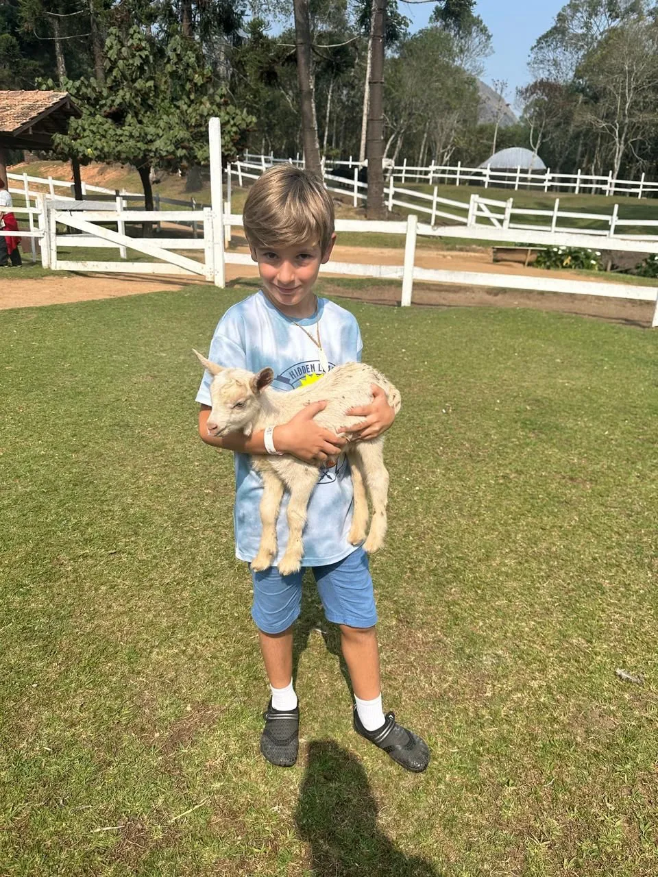 Criança segurando um cabrito na fazendinha do Hotel Fazenda São Moritz