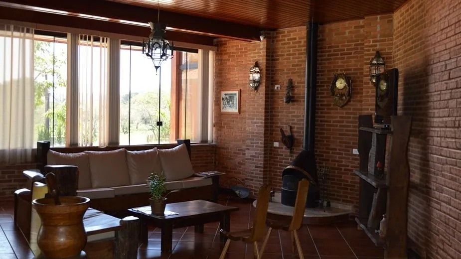 Sala de estar da recepção com sofá, lareira e parede de tijolo aparente
