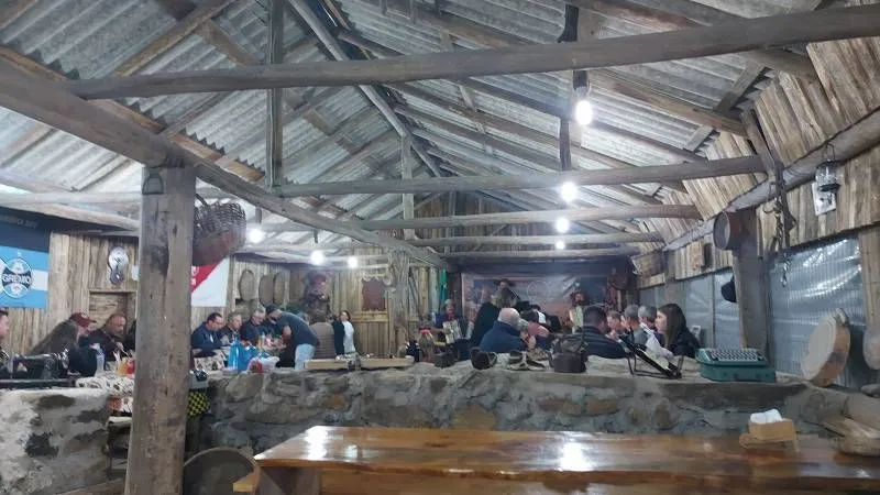 Salão rústico de pedra e madeira com hóspedes reunidos à mesa no Costão do Cambará Hotel Fazenda