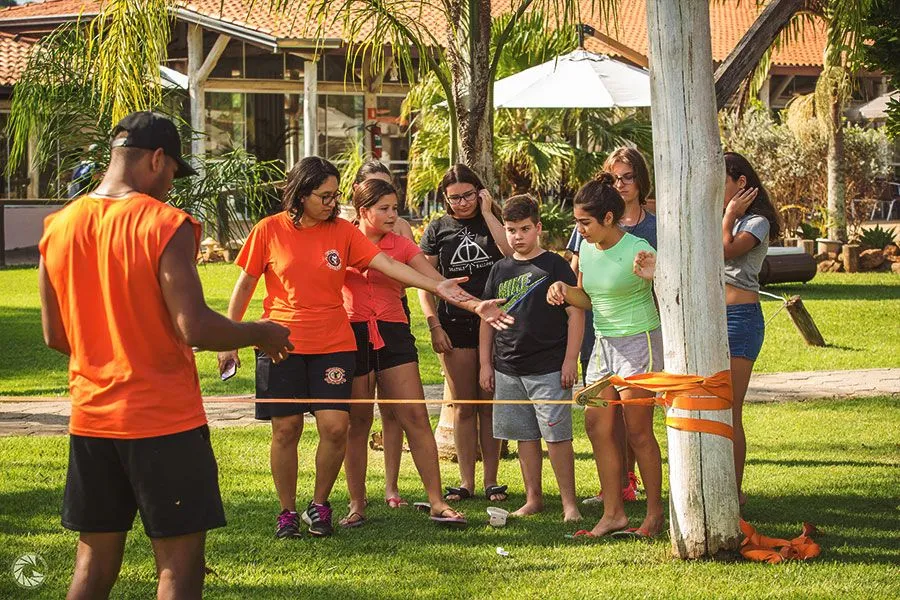 Equipe de recreação Pocotó conduzindo atividade em grupo com crianças e adolescentes no jardim