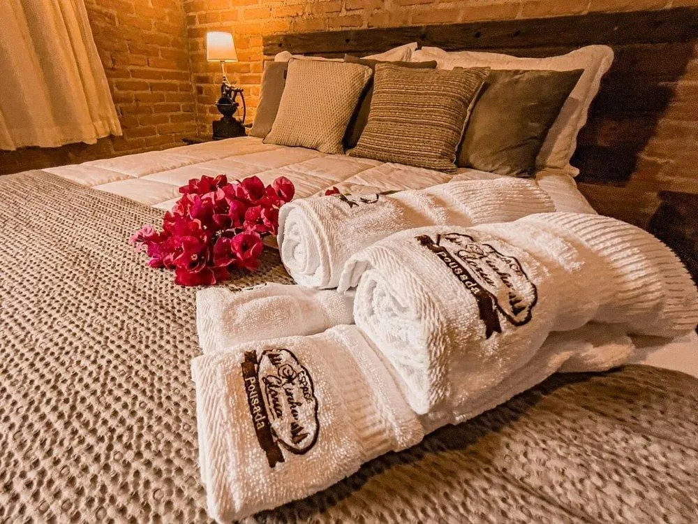 Cama de chalé com toalhas enroladas e flores vermelhas sobre o edredom