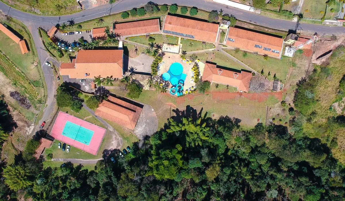 Vista aérea do conjunto do Hotel Fazenda Saint Nicolas com quadra, piscina e blocos de hospedagem