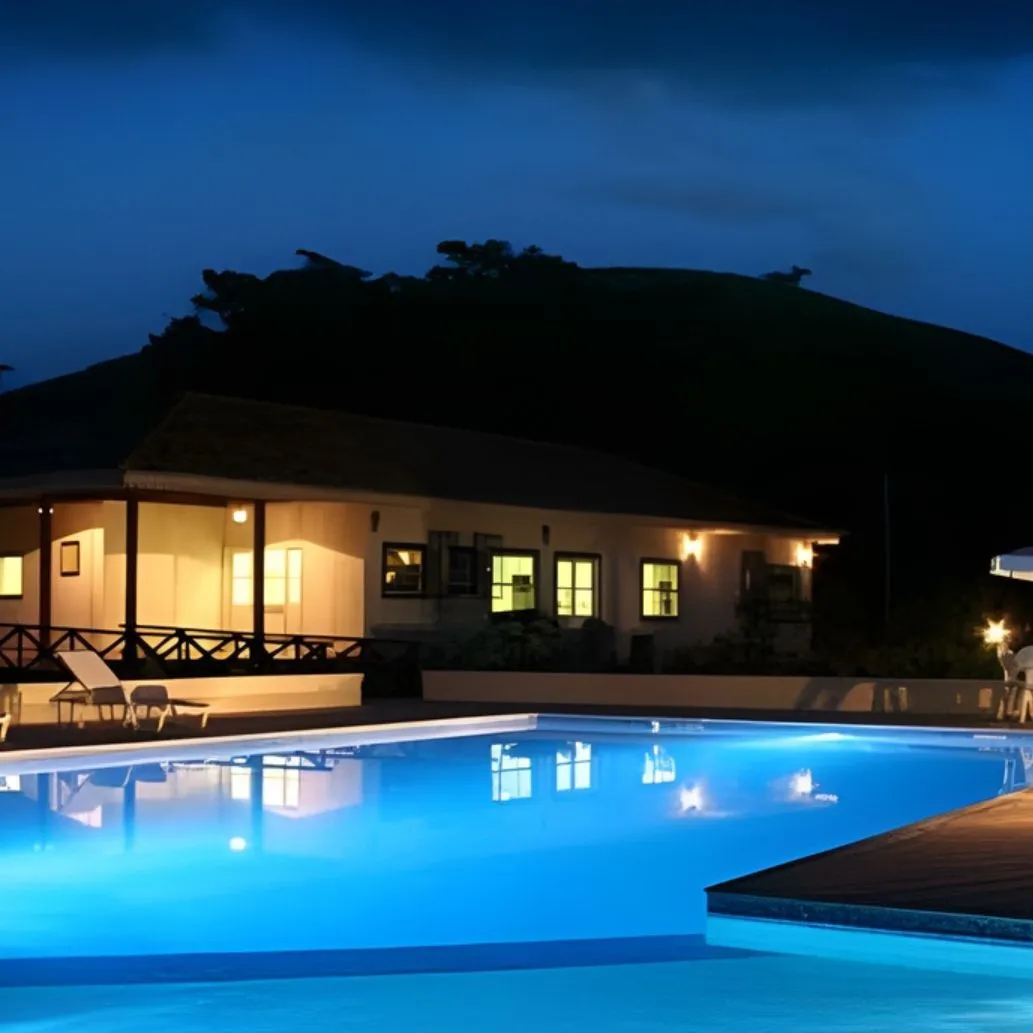 Piscina iluminada à noite com o casarão do Hotel Fazenda Florença ao fundo