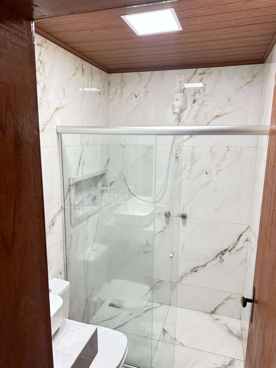 Banheiro em mármore com box de vidro de um apartamento do Sítio Green Valley