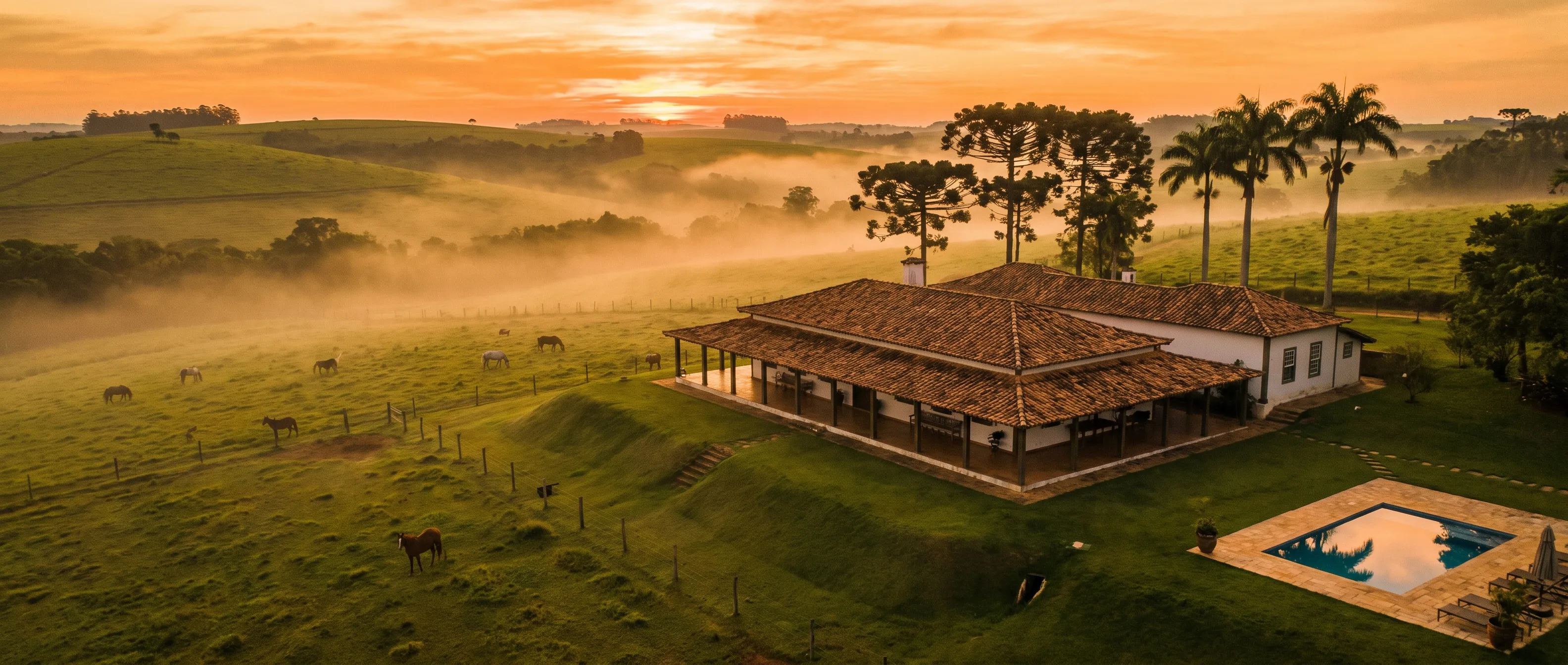 Hotel fazenda ao amanhecer, com neblina baixa sobre o pasto